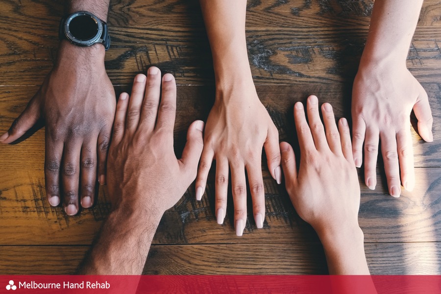 Image of different hands laying on a table.