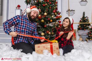 Two parents playfully wrapping Christmas presents