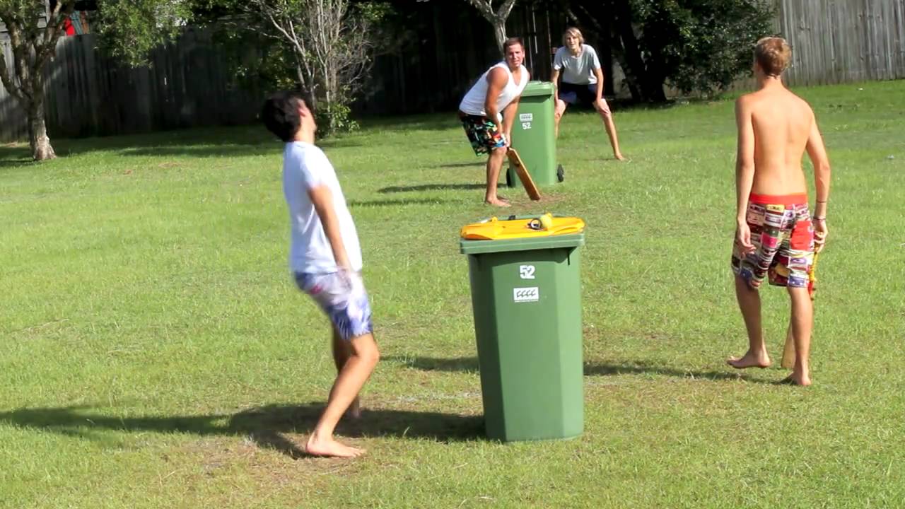 Kids playing backyard cricket with a wheelie bin as stumps