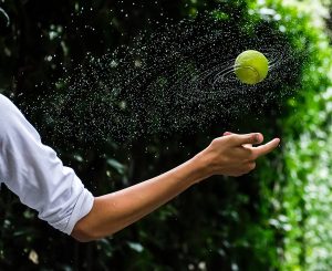 bowlers throws a wet tennis ball during a game of backyard cricket