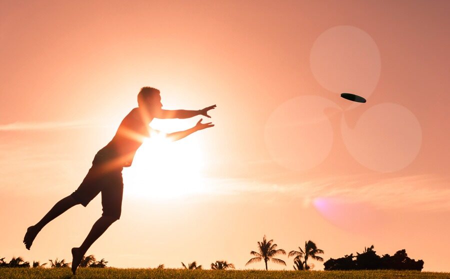 Male athlete playing frisbee at sunset