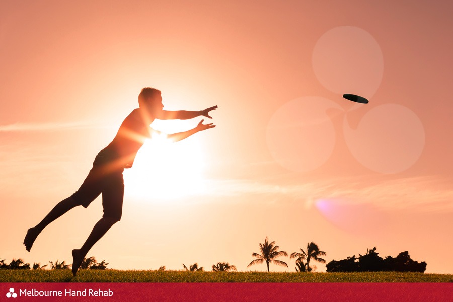 Male athlete playing frisbee at sunset