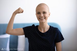 Self confident young woman combat against oncology looking at camera demonstrate muscles strength symbol