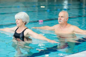 Older man and woman participating in a hand therapy hydrotherapy class