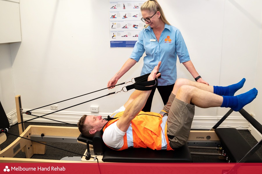 Pilates and hand therapy. Melbourne Hand Rehab client using a pilates reformer as part of there hand therapy treatment.