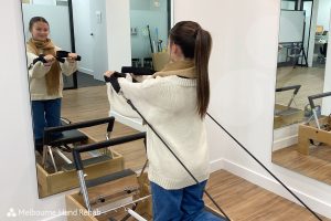 Pilates and hand therapy. Melbourne Hand Rehab client using a pilates reformer as part of there hand therapy treatment.