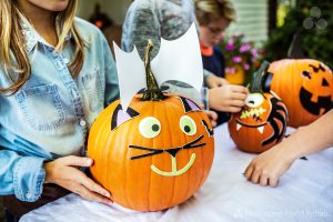 Children holding decorated pumpkins at table during Halloween.