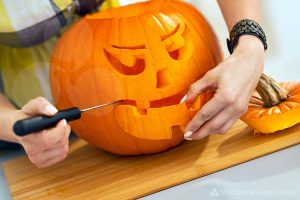 Closeup of person carving a big orange pumpkin Jack-O-Lantern