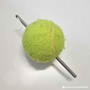 Image of a green tennis ball with a crochet needle pushed through it. Read our blog. Healing stitches: The therapeutic benefits of knitting and crocheting.