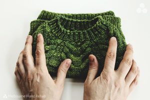 Image of hands caressing green knitted garment. Read our blog. Healing stitches: The therapeutic benefits of knitting and crocheting.