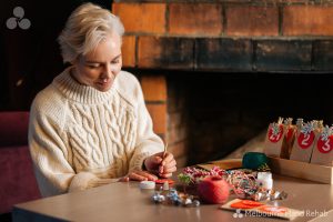 Seated woman preparing for xmas, new year and festive season, making decorations
