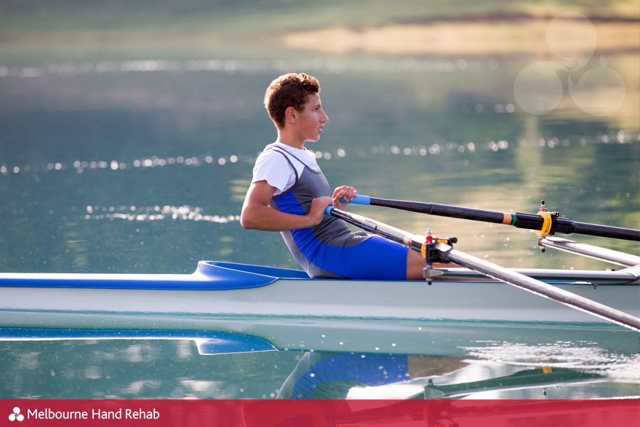 A Young single scull rowing competitor paddles on the tranquil lake.